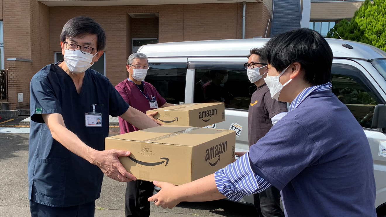 病院のみなさんにAmazonのダンボールにはいった寄付品を手渡す様子