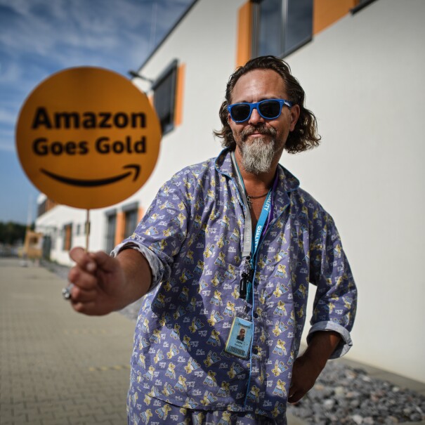 Amazon Mitarbeiter im Schlafanzug mit Amazon Goes Gold Schild