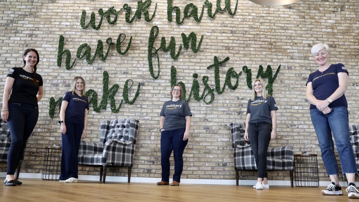Amazon employees, and ex-veterans from the Warriors@ affinity group staniding in front of a sign which reads "work hard, have fun, make history".