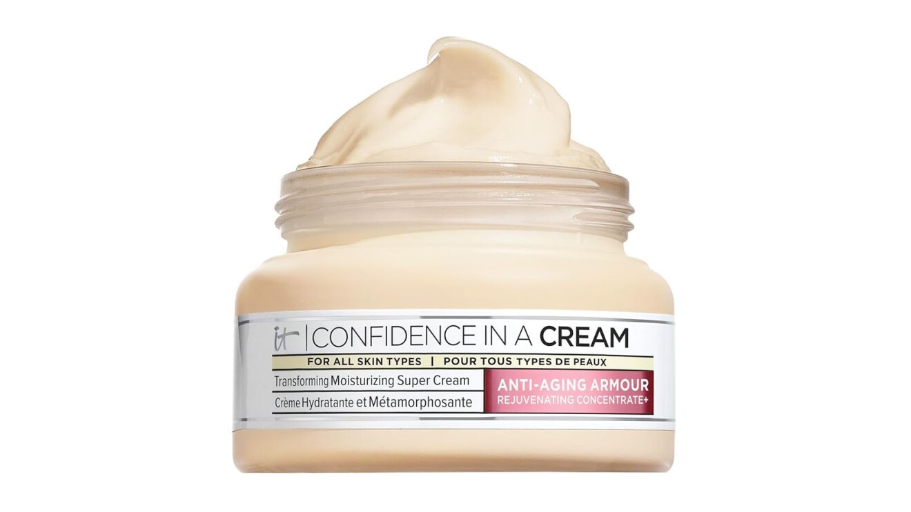 An image of a container of face cream from IT Cosmetics. It has a dollop of product at the top and writing on the face of the container that says "IT| Confidence in a Cream"