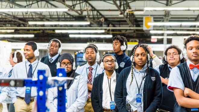 在俄亥俄州埃特纳市,高中生们穿着校服,戴着耳机参加亚马逊物流中心的参观活动。
