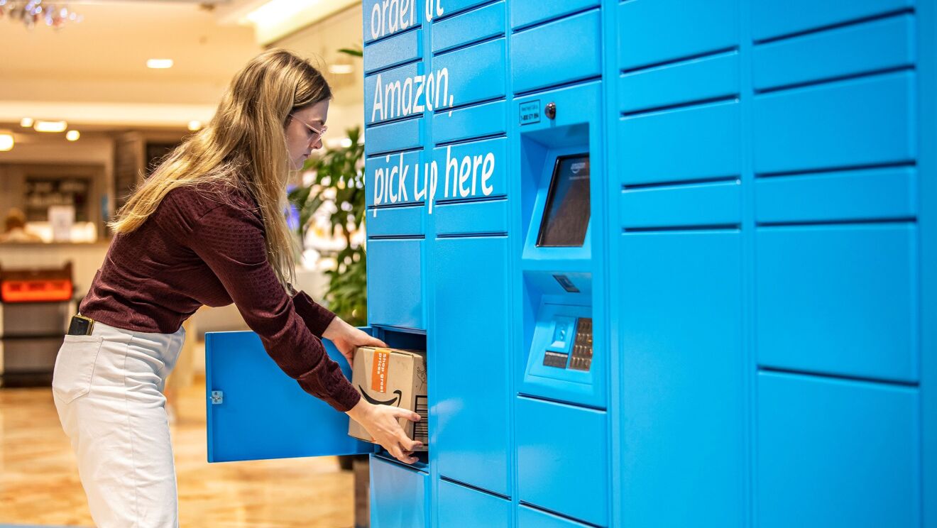 A woman in red wine shirt is picking up a package from Amazon Locker