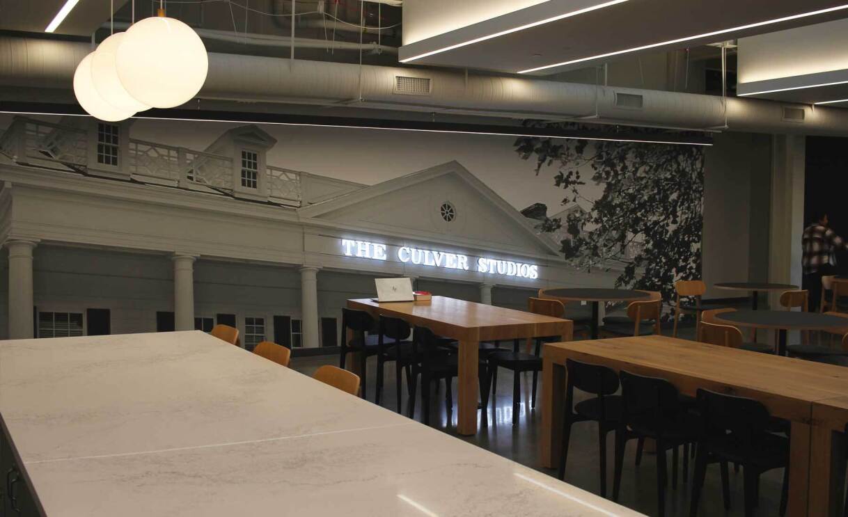 An image of a kitchen area in the Amazon office. There is a mural on the wall showing the Culver Studios mansion with lights on the letters.