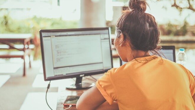 这张照片显示的是一位女士正在她的电脑上编程。