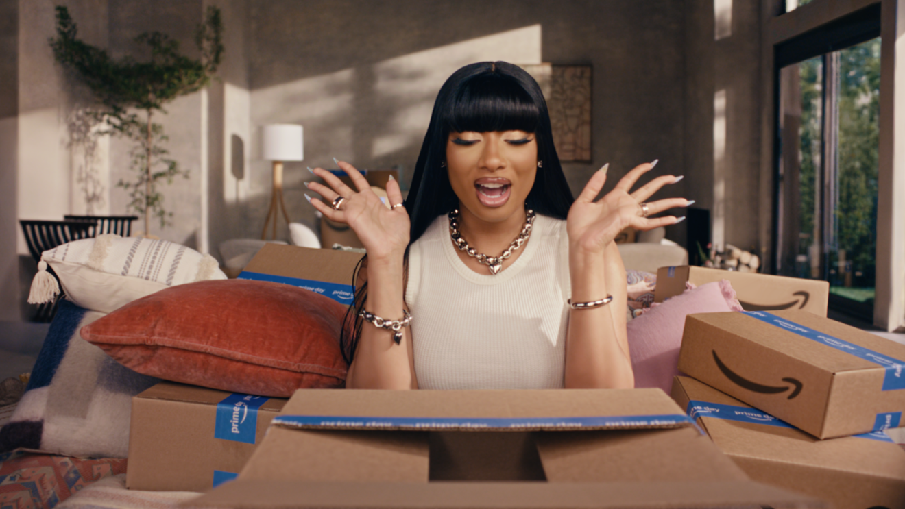 Megan Thee Stallion sitting in her living room opening Amazon boxes