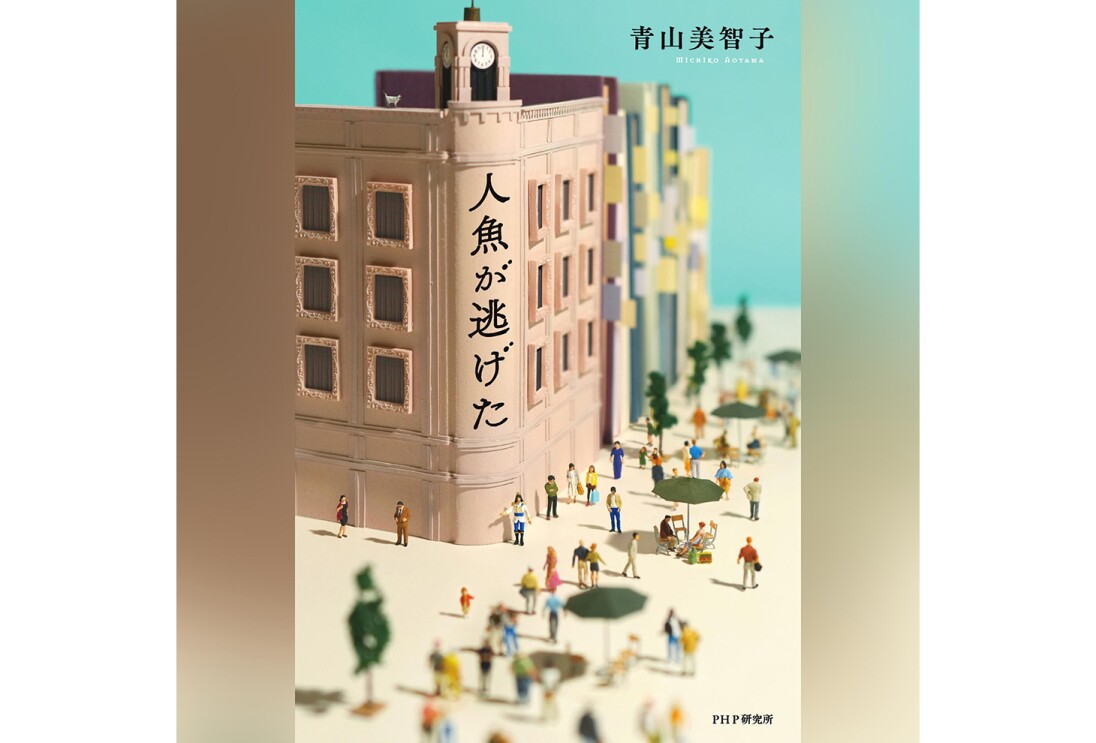 縦長の書籍カバー。建物と通りを表現したミニチュアの写真。時計台のあるベージュのビルの前の通りを小さい人形が多数歩く。建物に「人魚が逃げた」の文字。