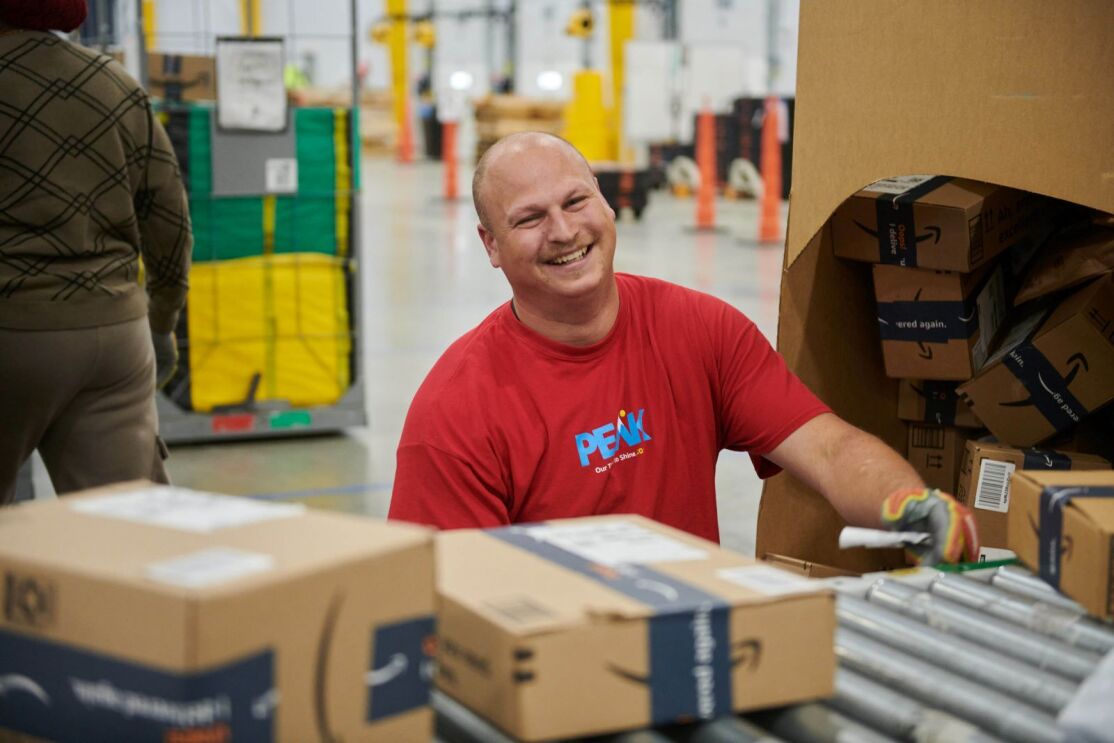 Cheerful employee sorting packages in distribution center
