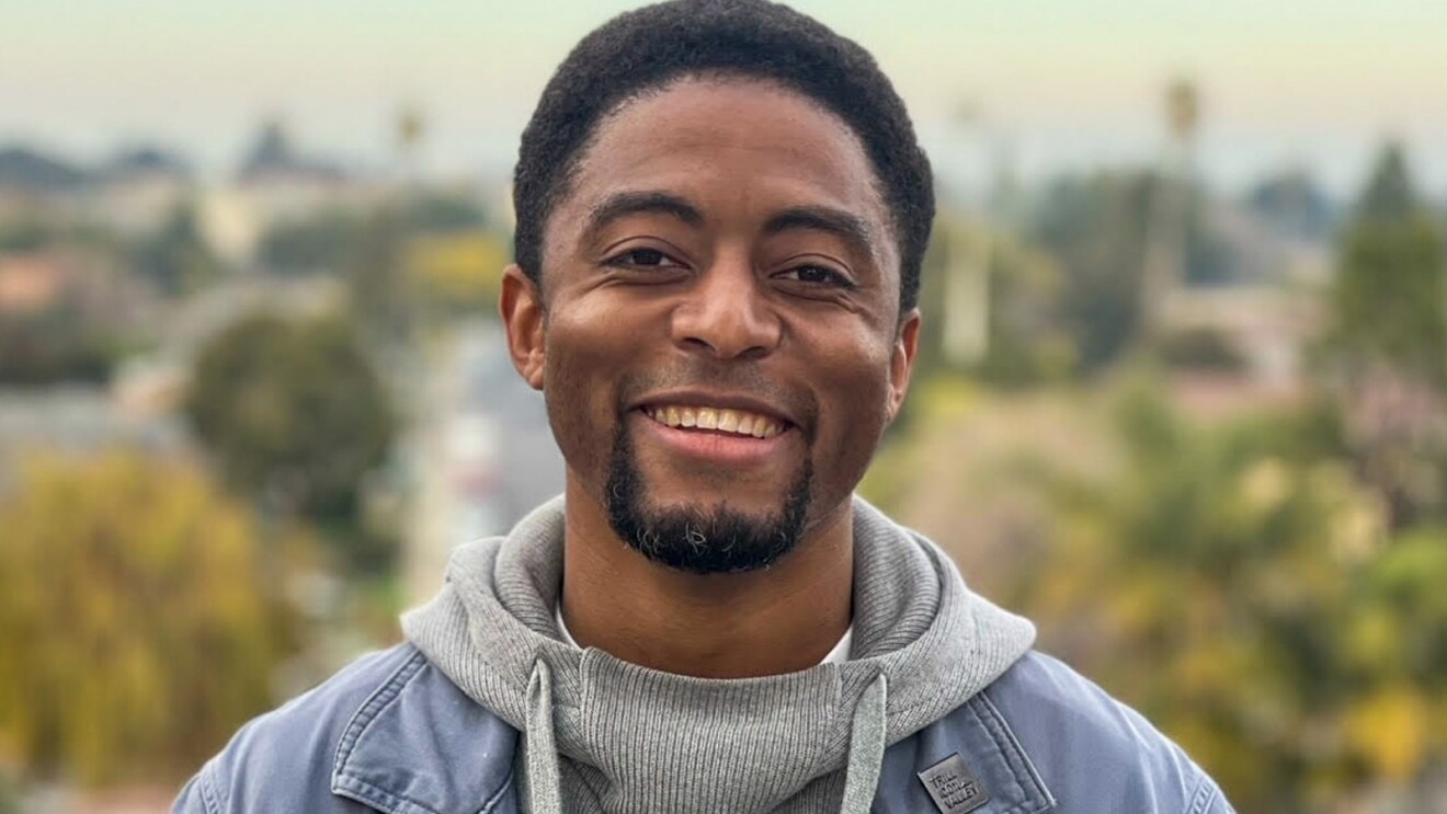 An image of a man smiling for a photo in front of a cityscape.