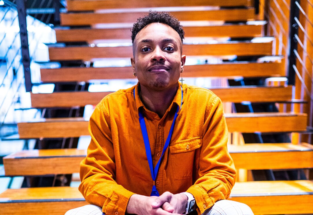 An image of a man smiling for a photo sitting on steps in an Amazon office.