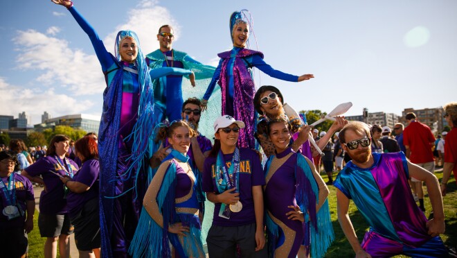 美国特奥会运动员帖子与事件在闭幕式上表演。特奥会的女运动员戴着金牌,而表演者包括三个踩高跷(两个女性穿着精致的头盔),一个骗子,和其他服装(有很多闪光的、边缘和图样)表明circus-themed表演。