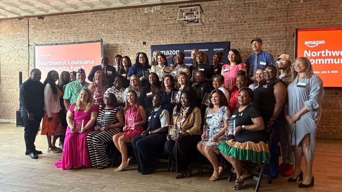 Large group of Amazon Community Award recipients and staff posing together at Northwest Louisiana event with Amazon branded displays