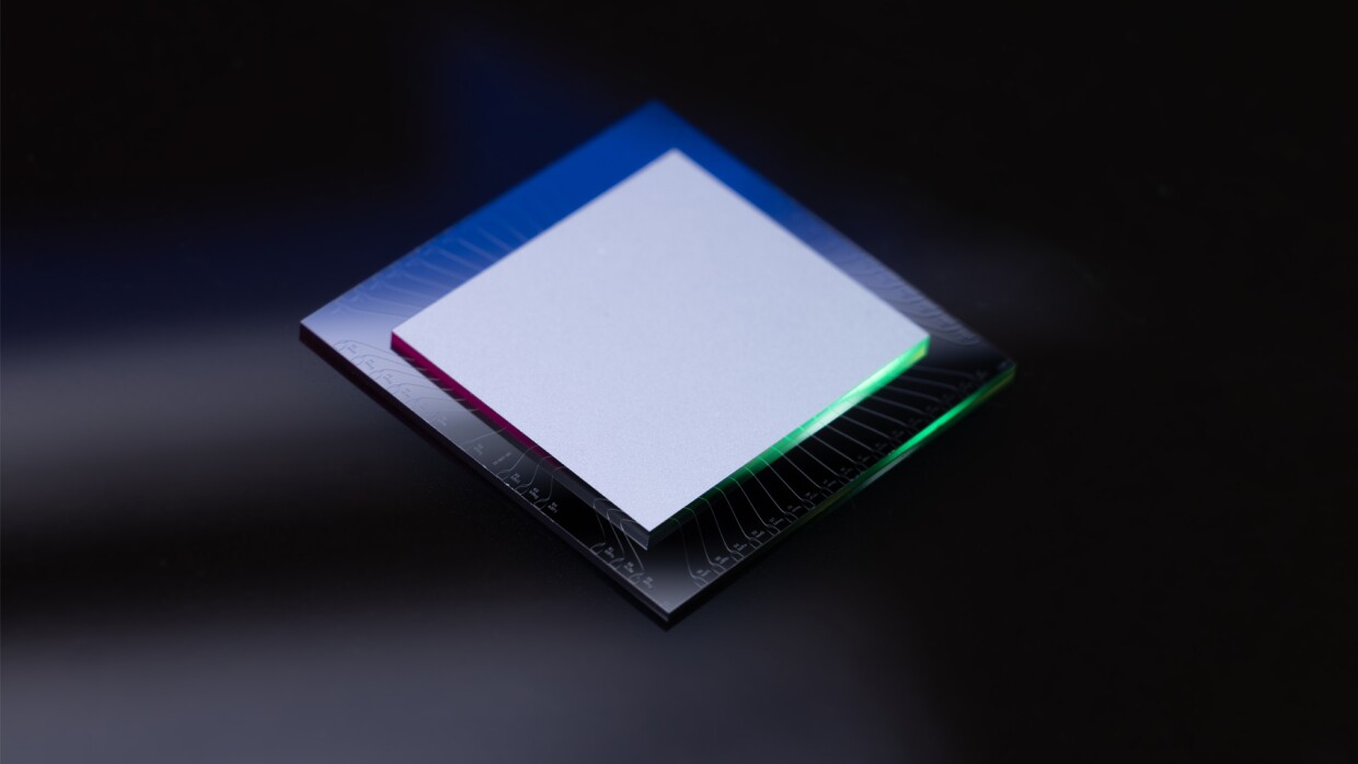 黒い背景に正方形の黒い金属プレートがあり、その上に一回り小さな正方形の白いプレートがのっている。どちらのプレートも、右下側の断面が黄緑に光っている