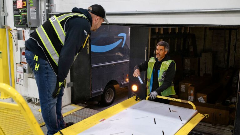 Amazon delivery workers loading packages onto truck at warehouse