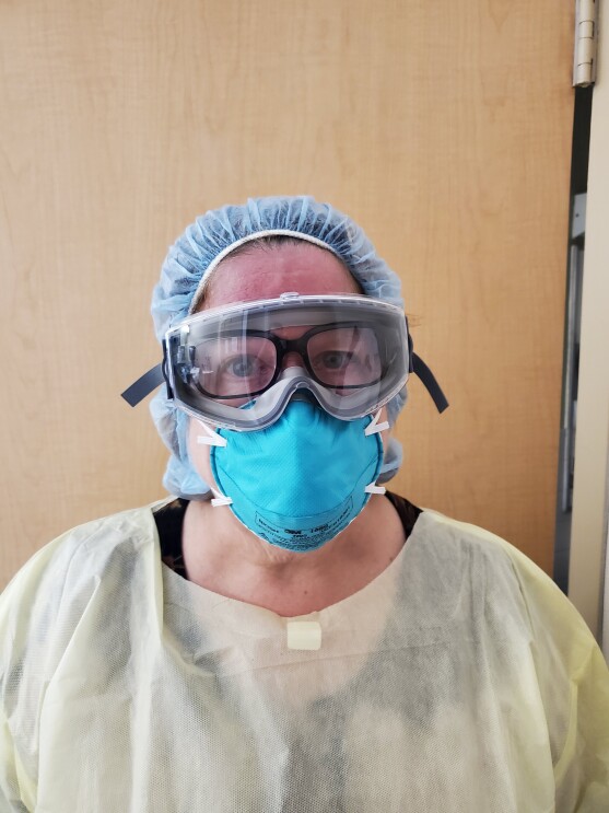 A woman wearing PPE has her Echo Frames on under her goggles, as a Physician's Assistant. 