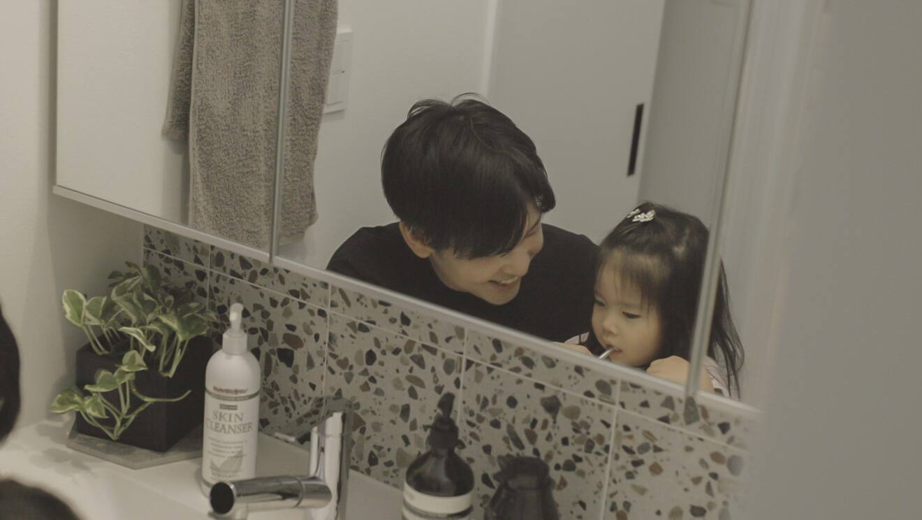 洗面台で子どもの歯磨きを見守るパパさん