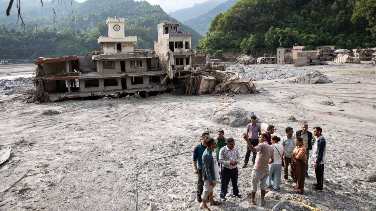A group of people stood among debris with a ruined building behind