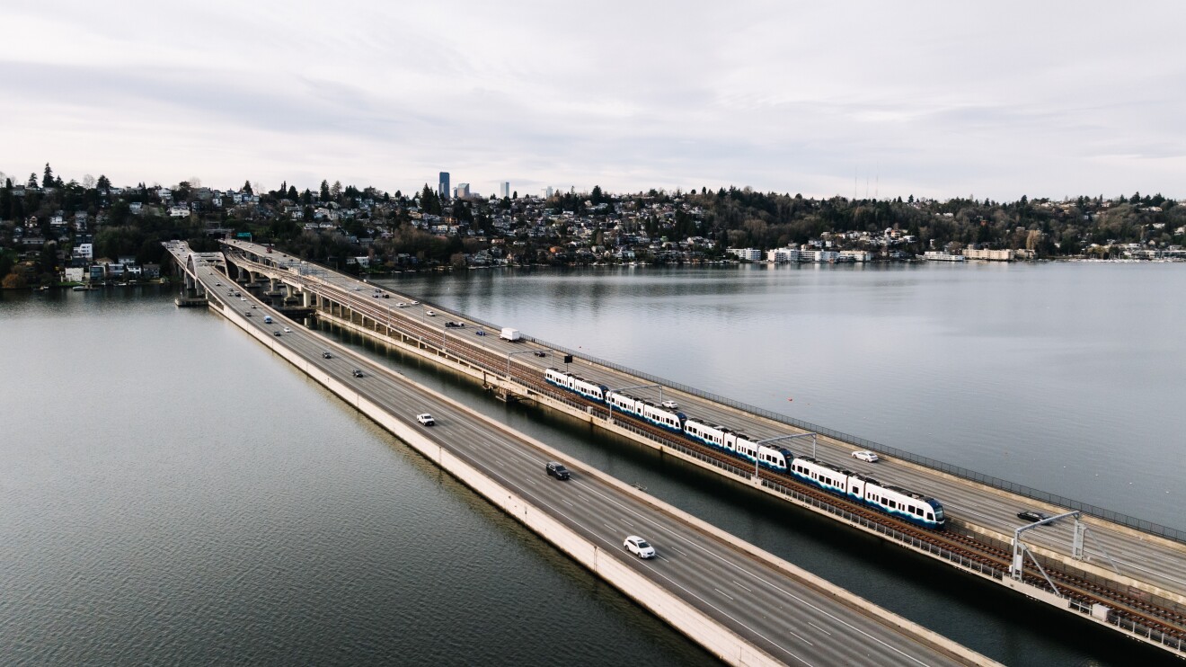 Long bridge spanning lake with city skyline in background, the Seattle Crosslake Connection
