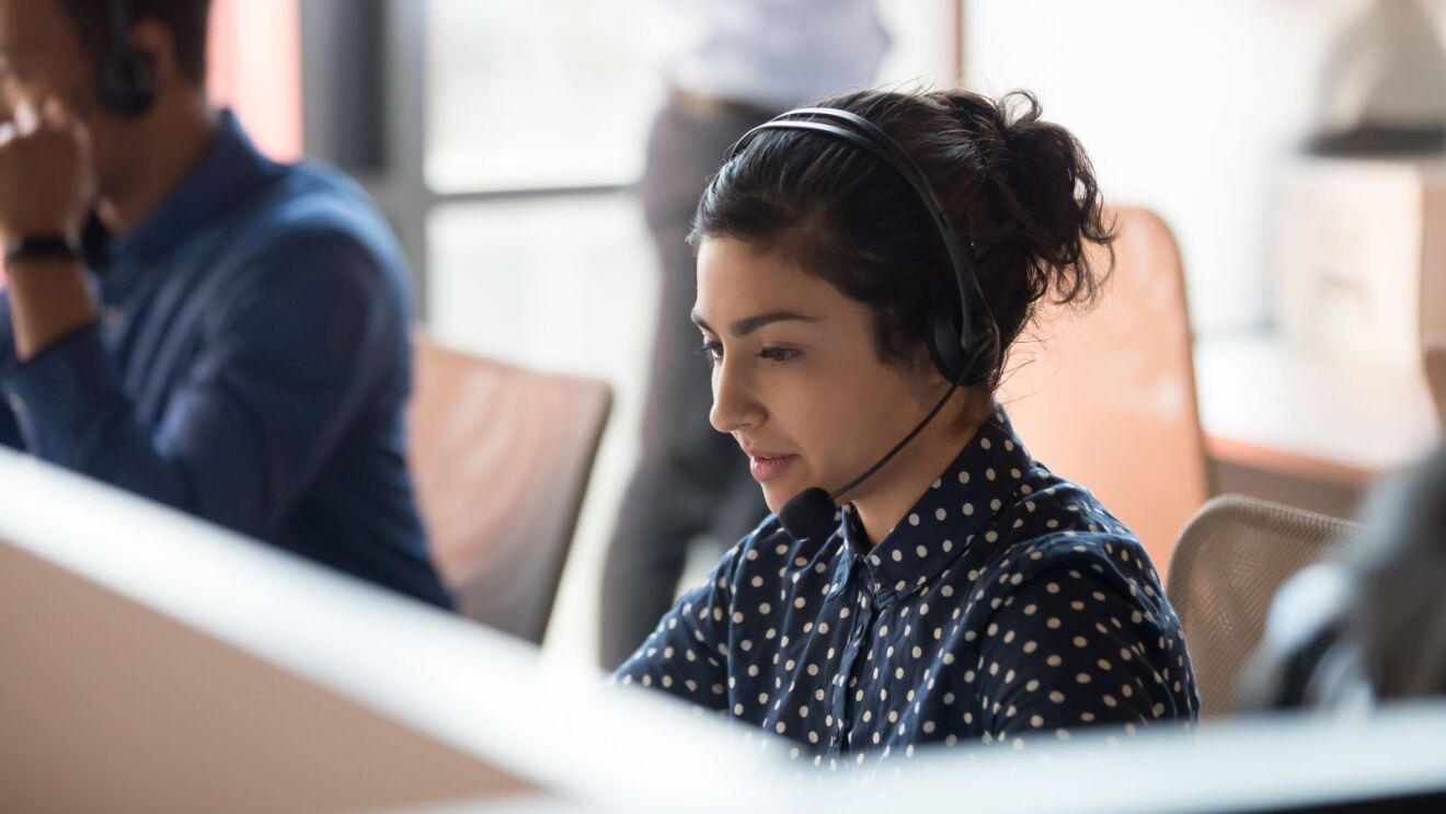 Call center employee focused on computer screen wearing a headset