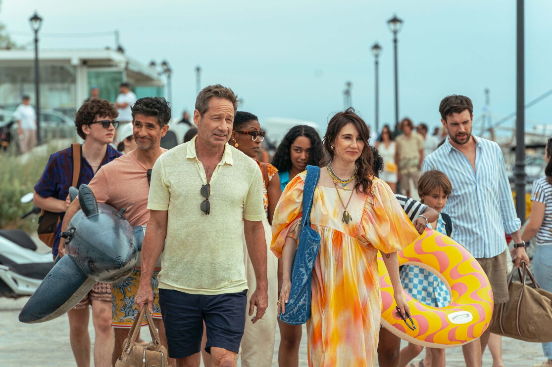 A family walk on the beach crying bags and inflatable swim items