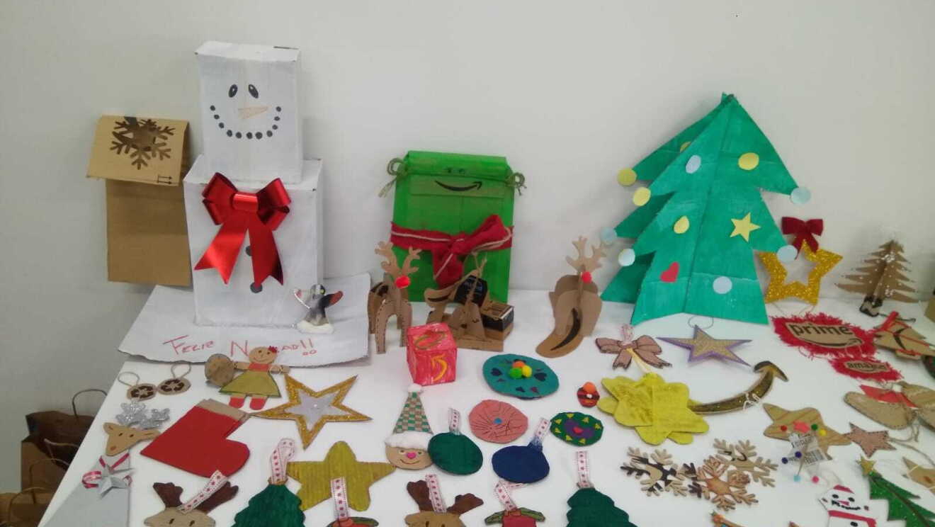 Adorno Navideño de MAD4. En una mesa de color blanco está lleno de decoraciones para colgar en el árbol: renos, árboles, camoanas, papá noel, estrella fugaz, estrellas.