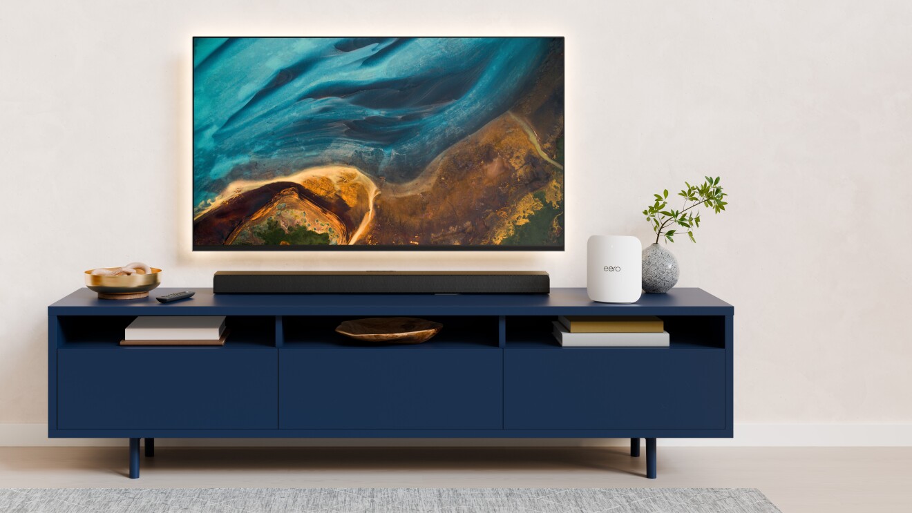 eero sat on a blue TV stand below a mounted TV displaying marbled colors