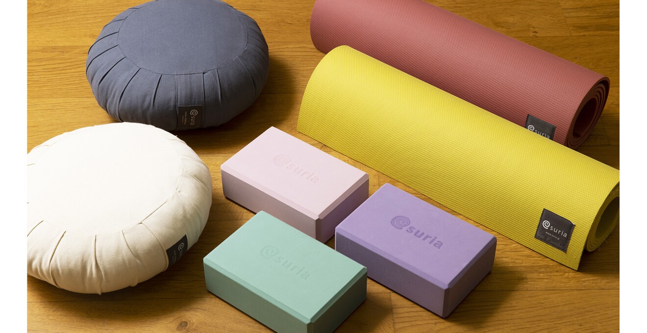 白とインディゴ色の丸くて厚めの座布、ピンク・紫・グリーンのヨガブロック、赤と黄色のヨガマット