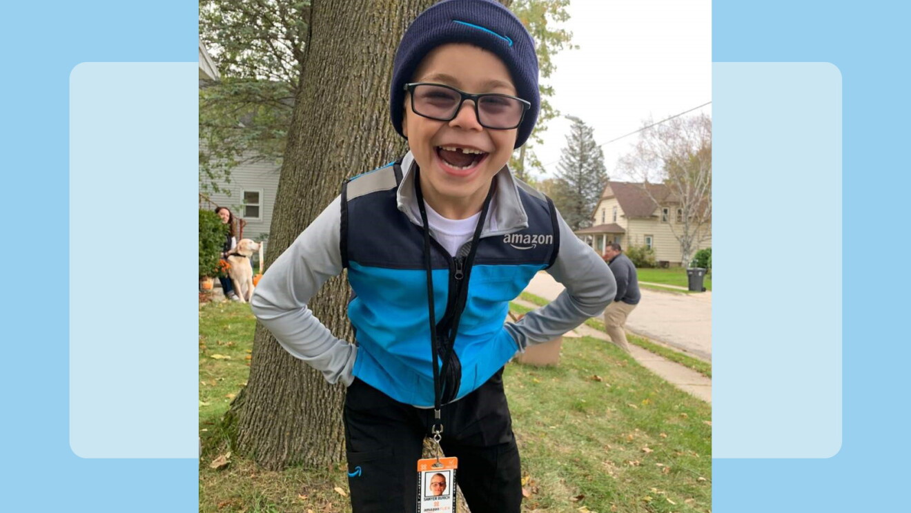 An image of a child wearing an Amazon delivery costume smiling with a blue background.