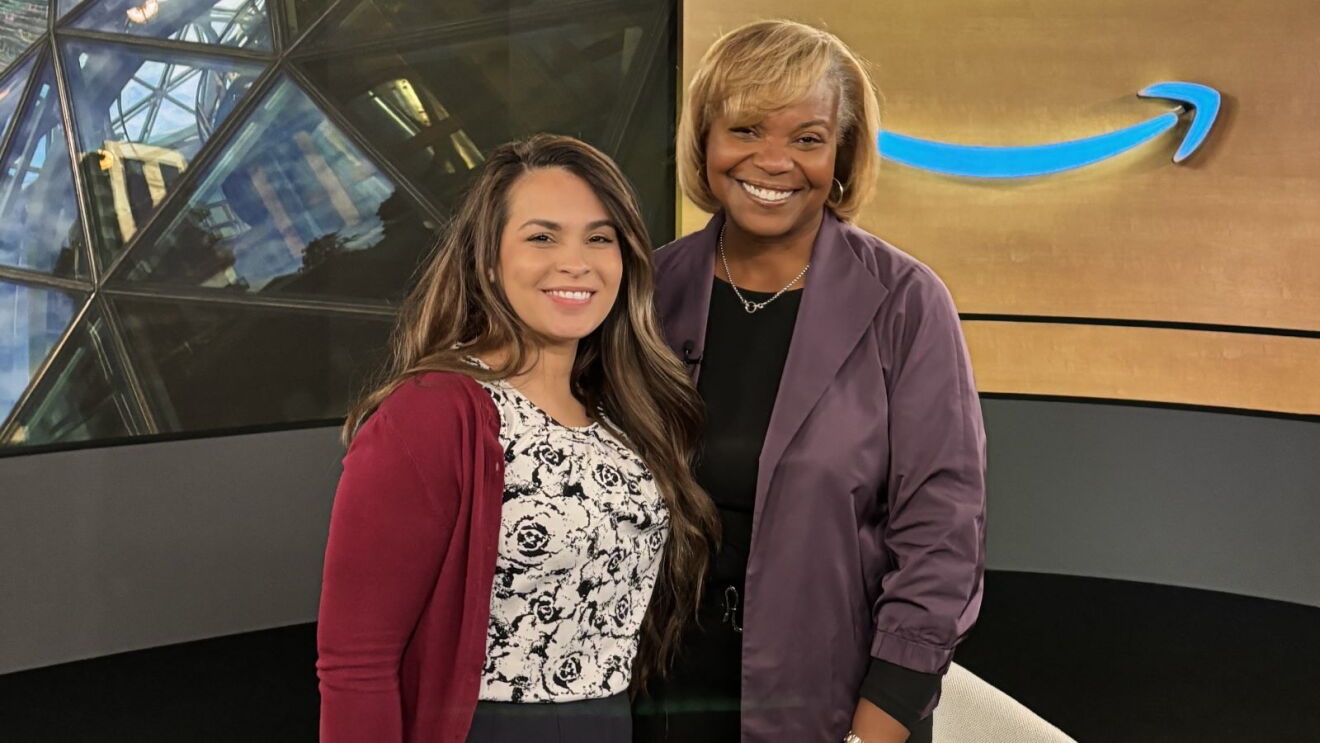 Two smiling women posing together in front of Amazon logo