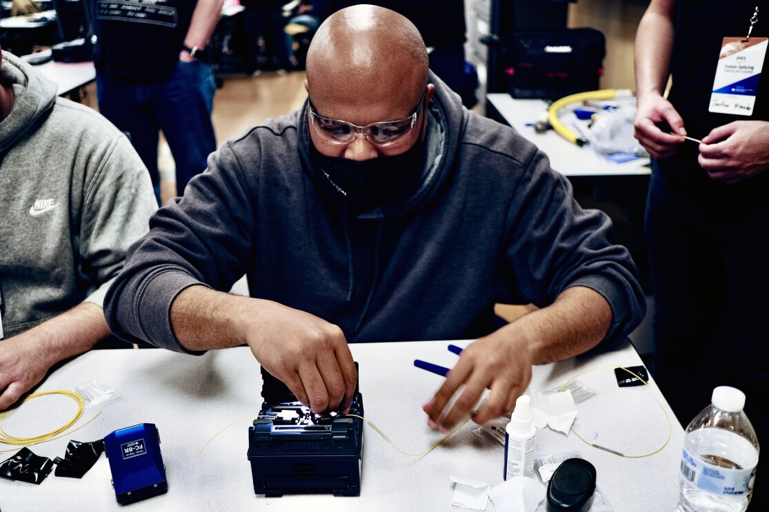 An image of a man working on a piece of technology hardware while wearing safety glasses. 