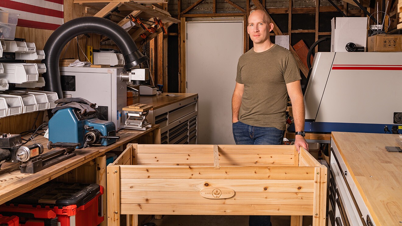 A photo of a cedar wood planter in a work shop and the owner of Boldly Growing.