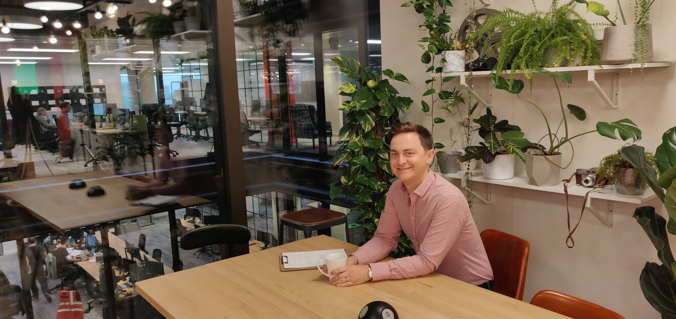 Dave Brittain smiling and sat at a desk in Amazon head office 