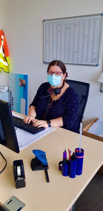 Silvana mit Maske am Schreibtisch.