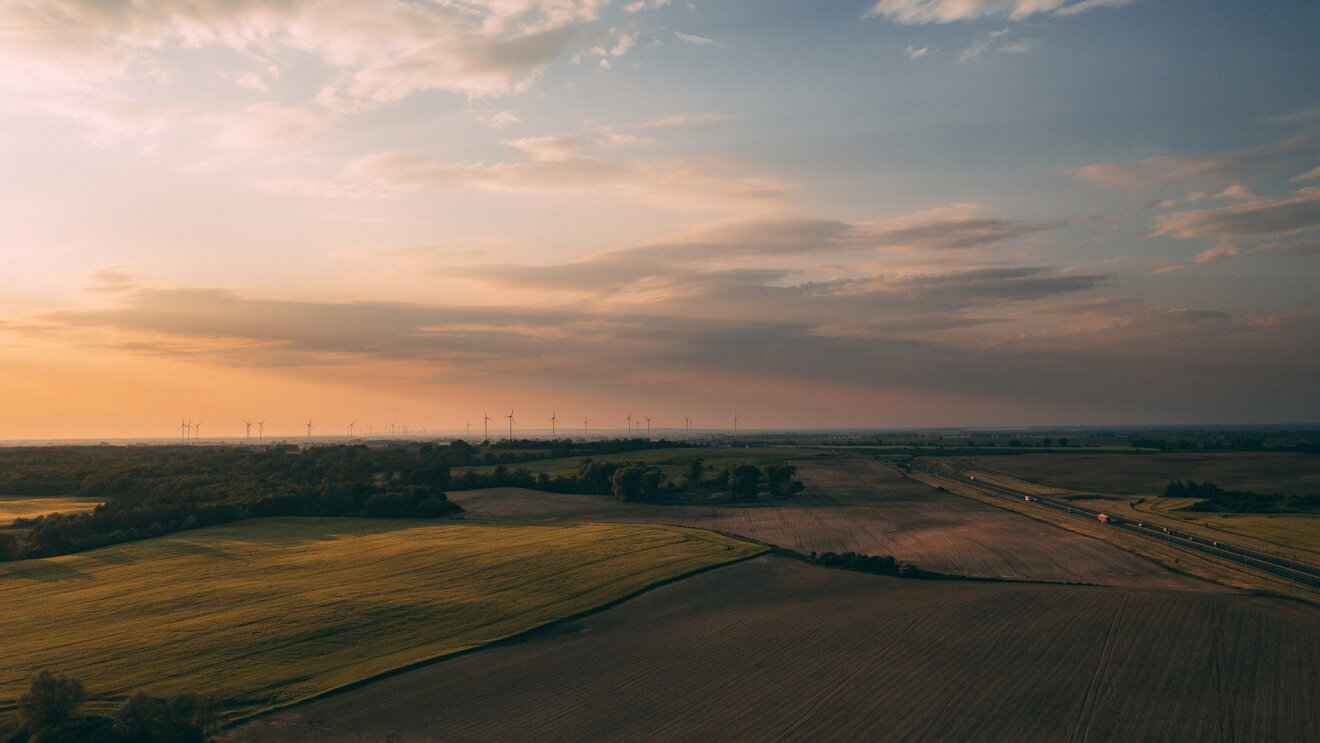 The Climate Pledge_Amazon_Felder im Sonnenuntergang_Windräder