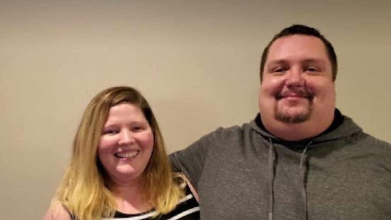 A woman and man stand together, smiles on their faces.