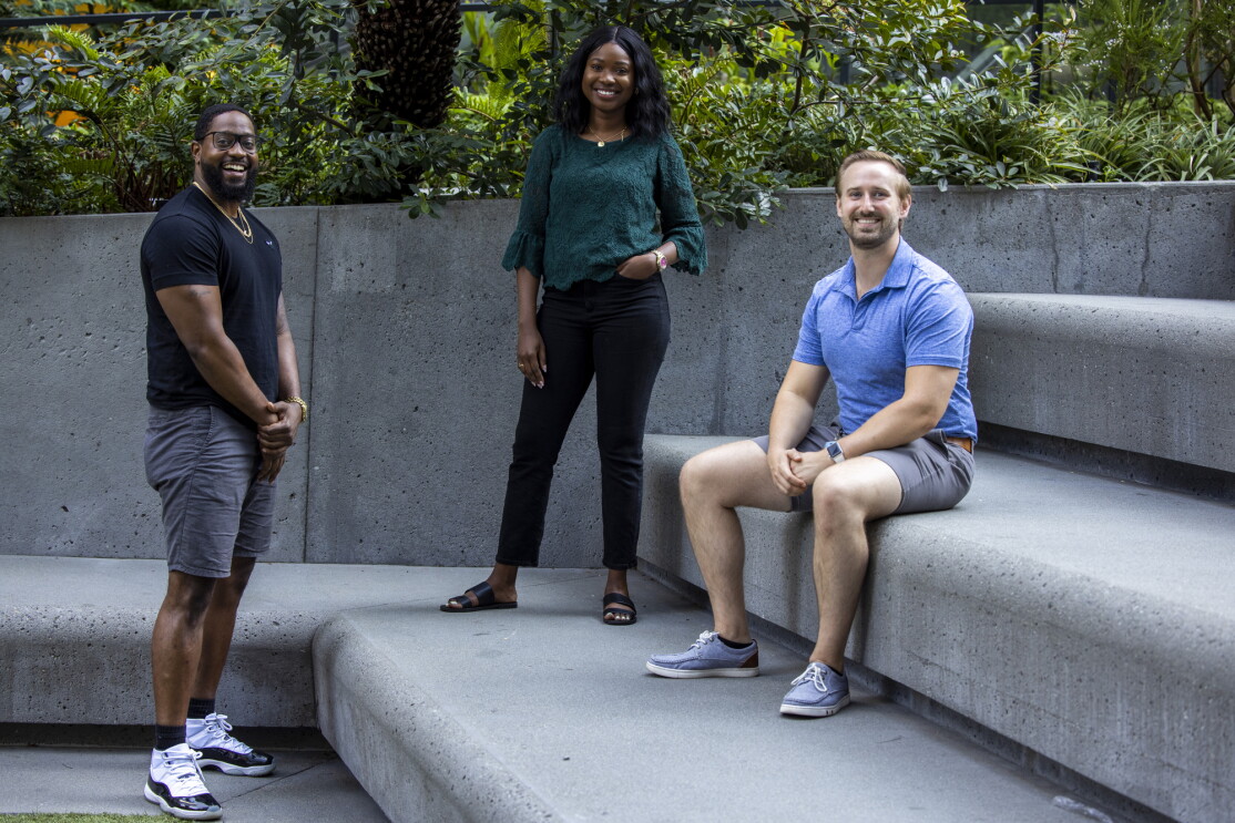 A woman and two men on a tiered concrete seating area.