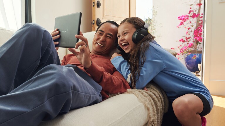 A father and daughter share a laugh while streaming on their Fire tablet.