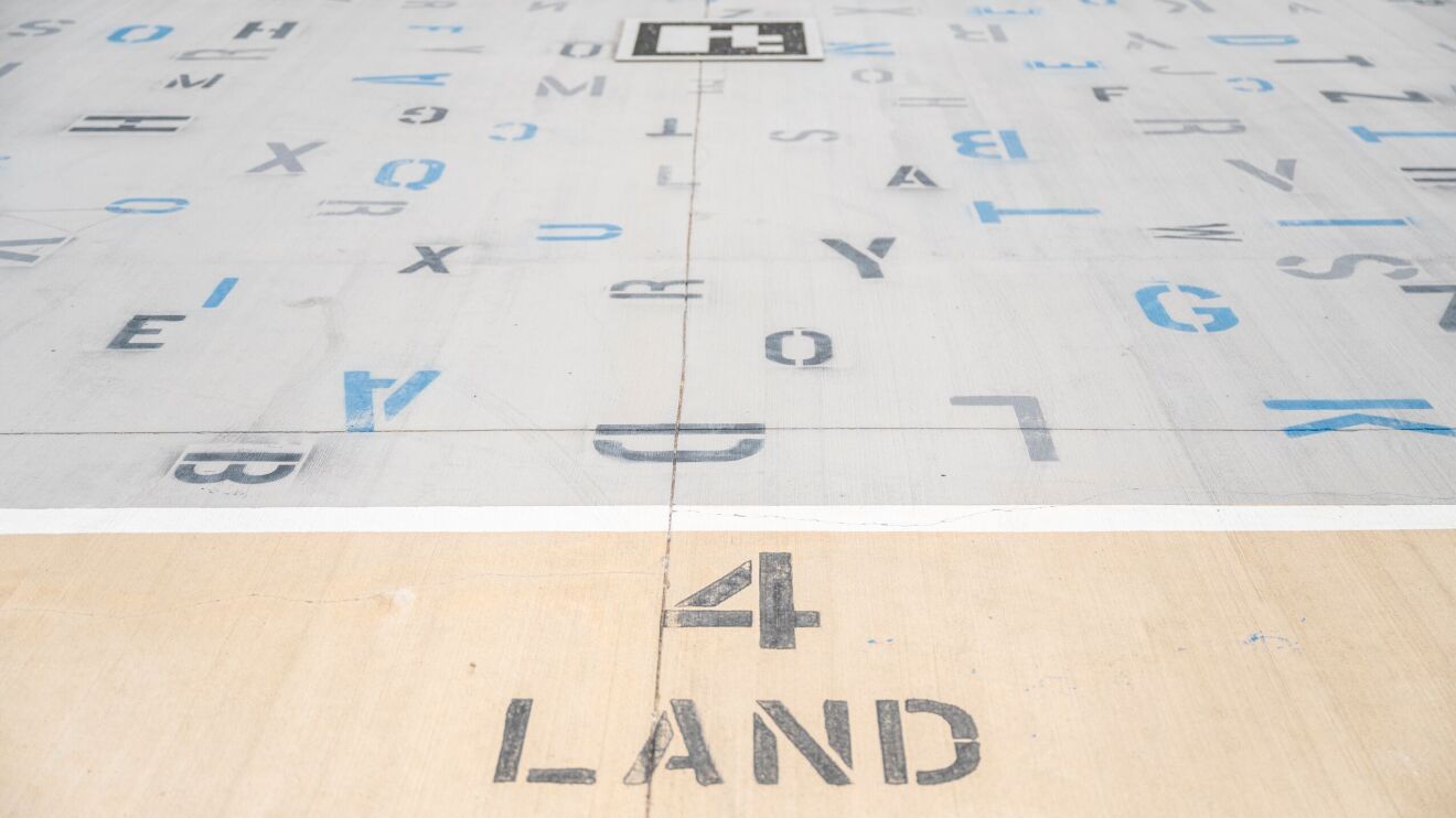 An image of the landing pad for the Prime Air delivery drones. There are several numbers and letters on the pad along with text that reads "4 LAND"