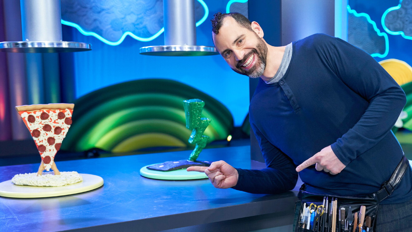 An image of Jason Loik pointing to two sculptures made out of Play-Doh.