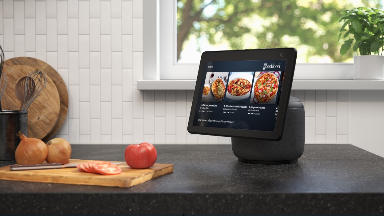 Alexa device on kitchen worktop next to wooden chopping board and fruit 