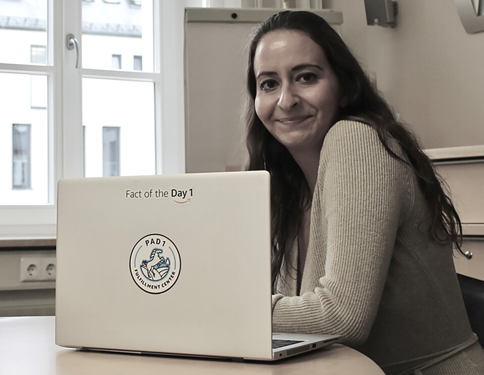 Eine junge Frau mit langen dunklen Haaren vor einem Laptop