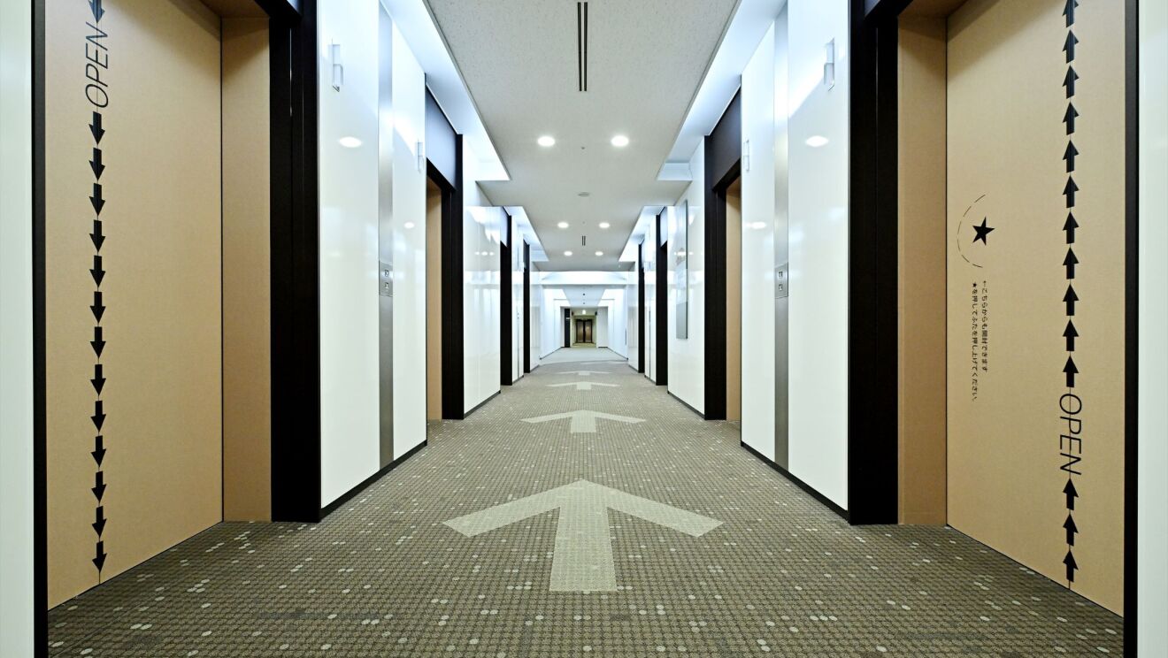 エレベーターホールのカーペットに描かれている矢印。その両サイドにエレベーター