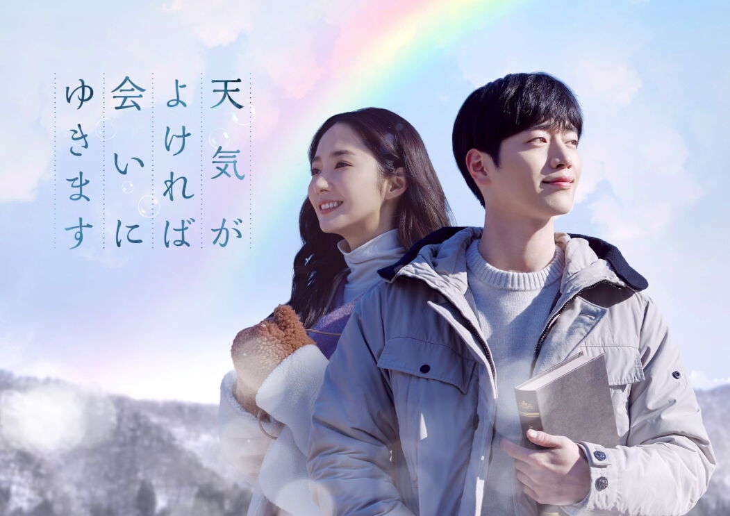 冬の服装をして、本を持っている男性と女性。その背景には雪山があり、空に虹がかかっている