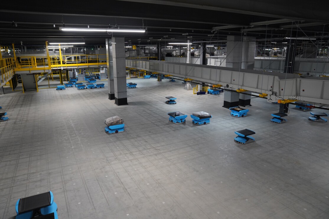 An image of small blue robots on the floor of the sortation center. They are carrying packages.
