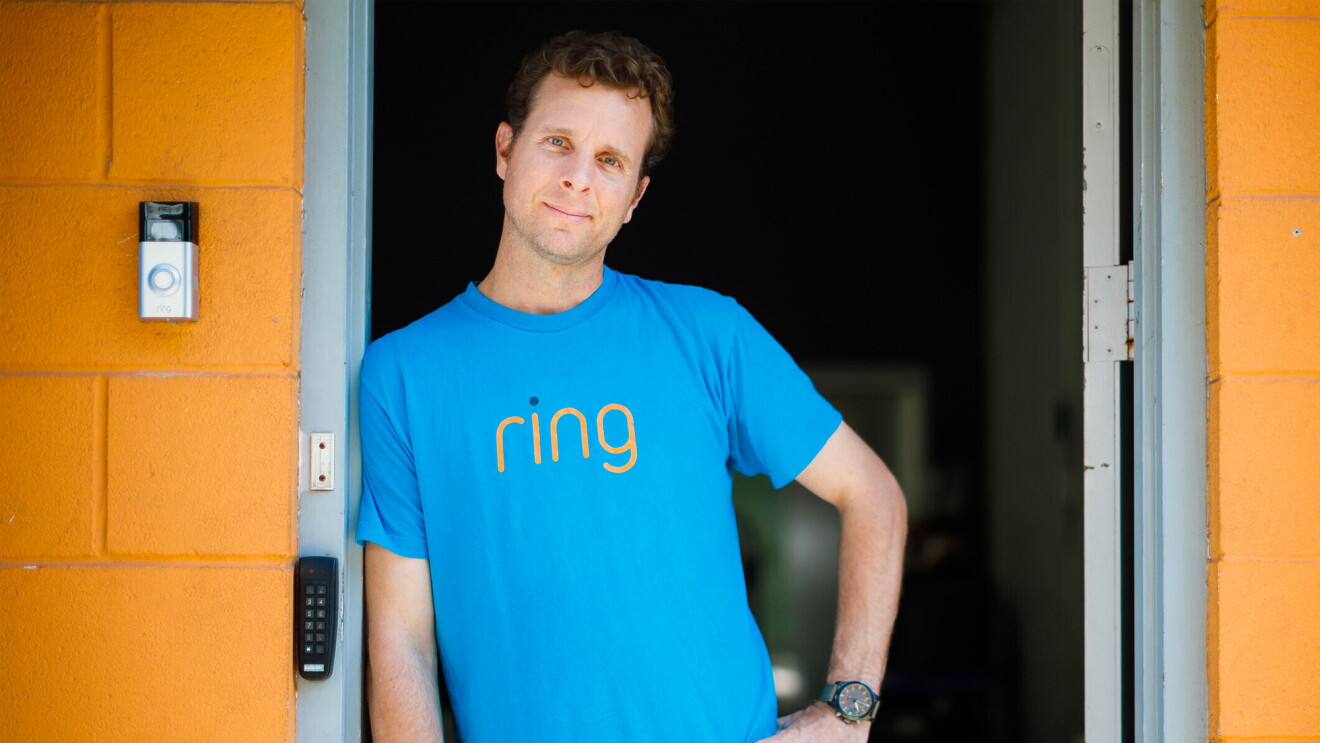 Jaime Siminoff wears a blue Ring t-shirt and stands in doorway with yellow walls