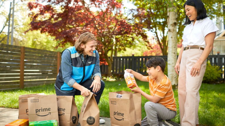 Family unboxing Amazon Prime orders in backyard with colorful fall foliage