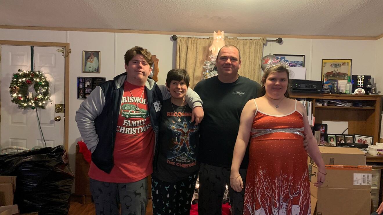 An image of a family standing and smiling for a photo in their home.