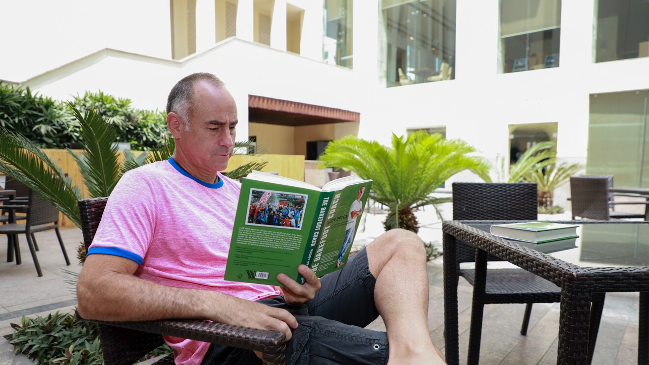 Paddy Upton on a chair  reading a book