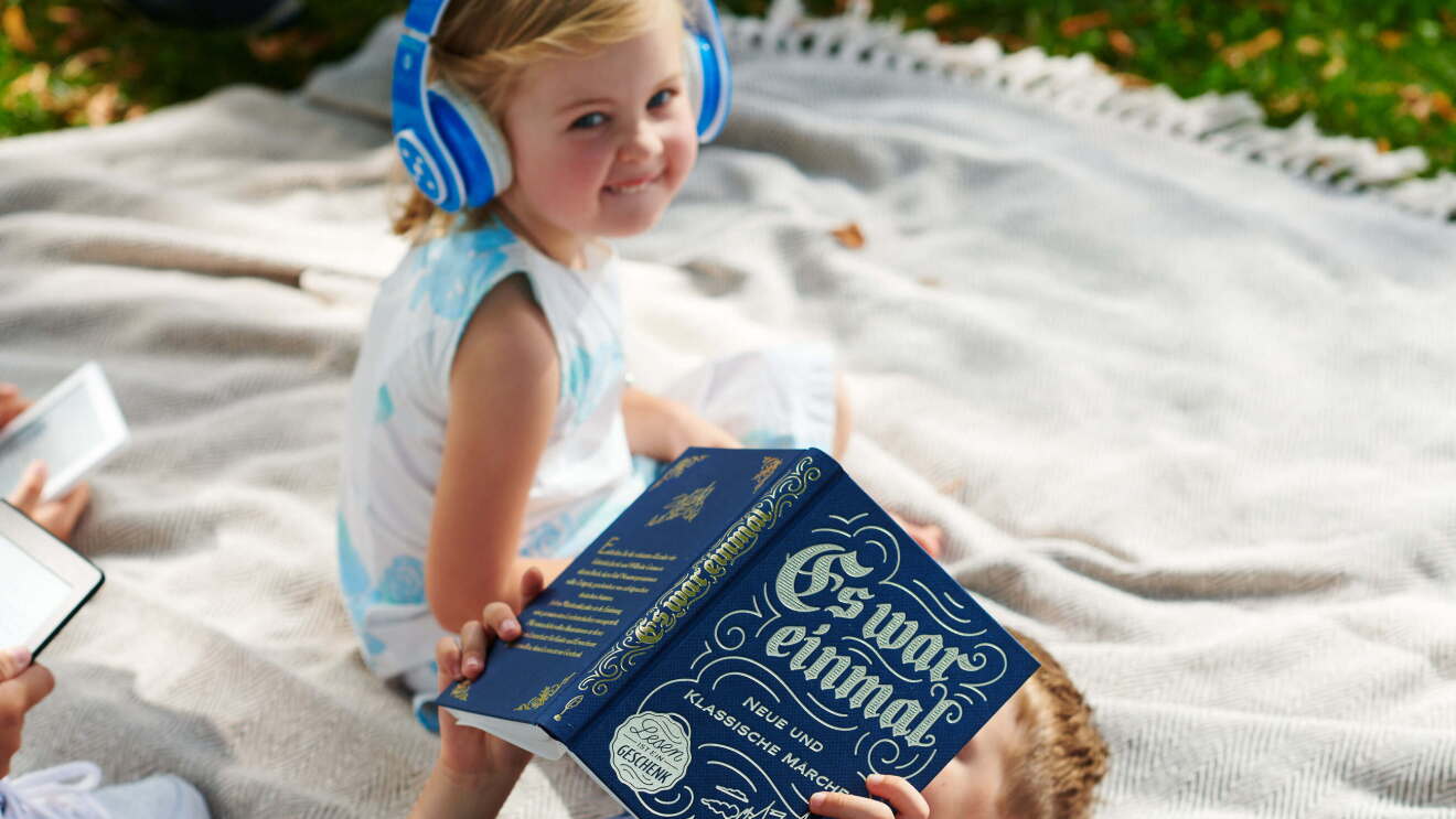 Kinder Lesen Märchen auf einer Picknickdecke