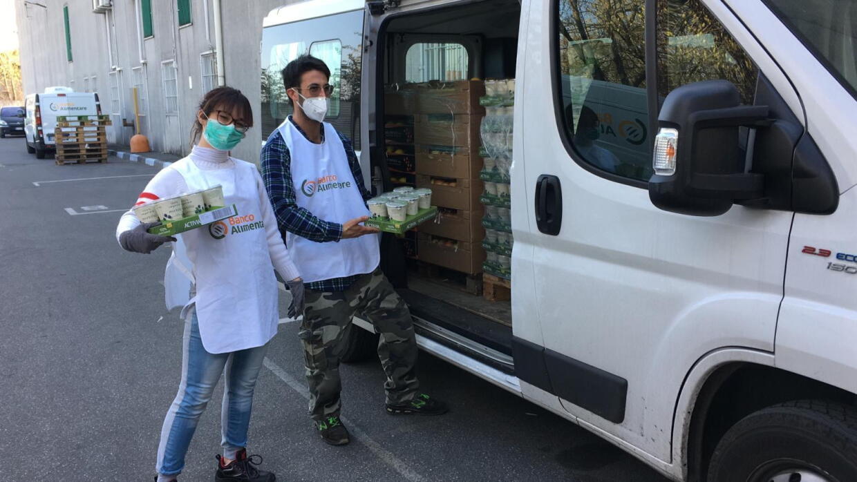 Due volontari di Banco Alimentare Lombardia davanti a un furgone con i pasti. 