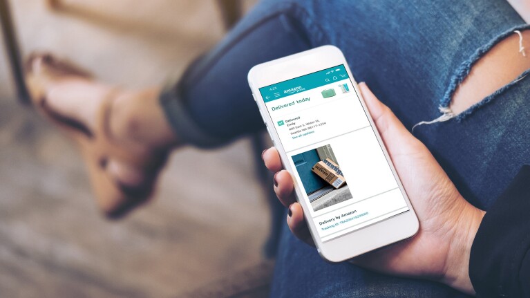 A woman looking at a phone and on the screen you can see the delivery confirmation of an Amazon package.